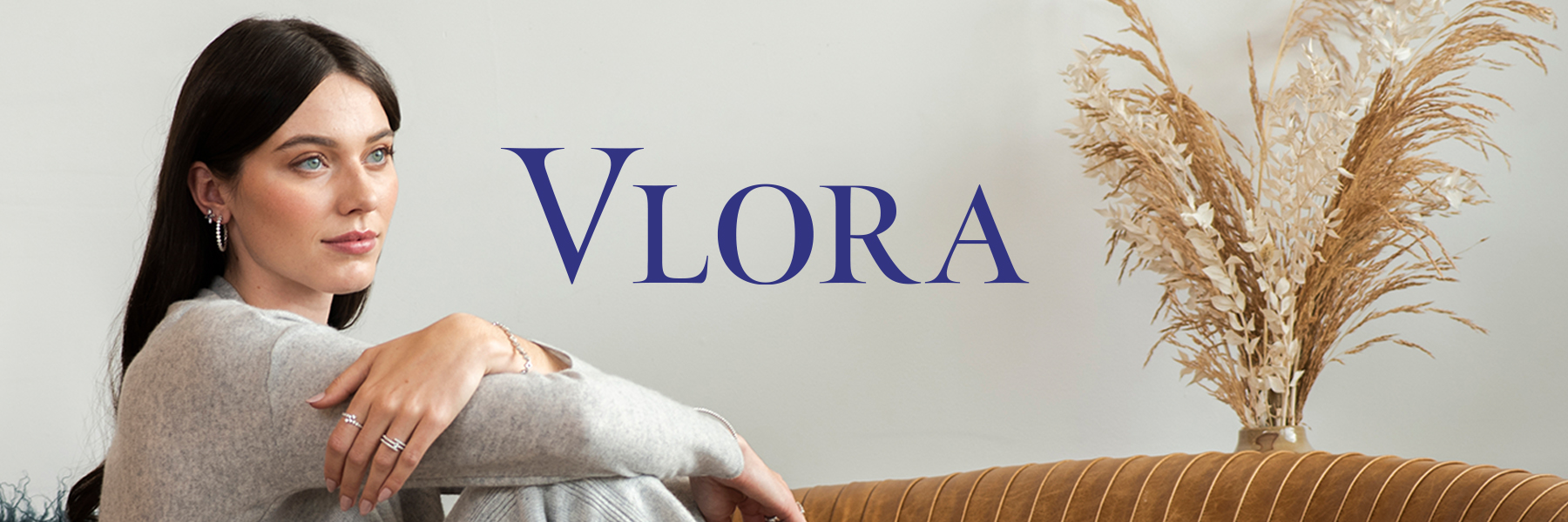 Vlora Rewards logo centered on top of photo of model wearing Vlora jewelry